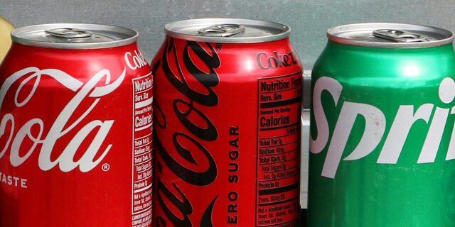 Row of canned sodas: Coca-Cola, Coca-Cola Zero Sugar, and Sprite