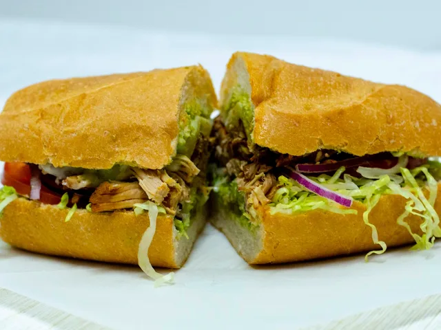 Torta De Carnitas sandwich with roasted pork and avocado, halved