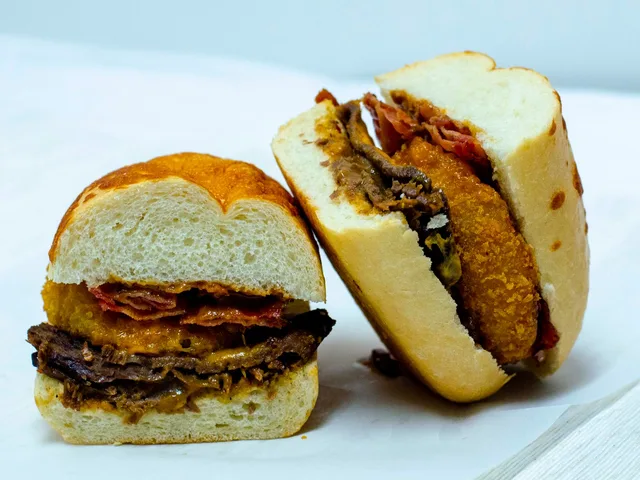 Tri Tip The Ringer sandwich with onion rings and bacon, halved